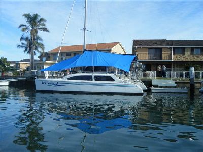 Catamaran with a blue canvas cover at a jetty