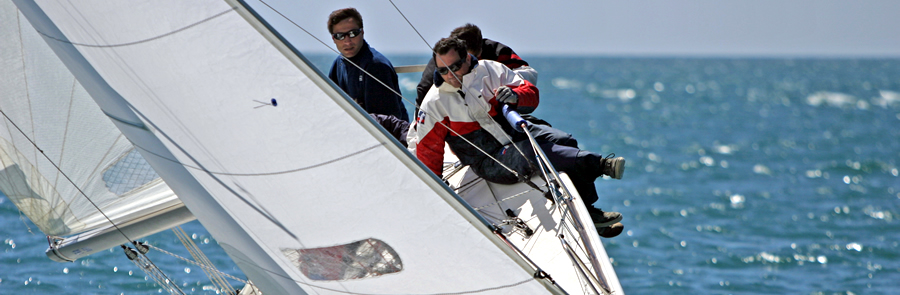 A crew hiking out on a racing yacht under full sail